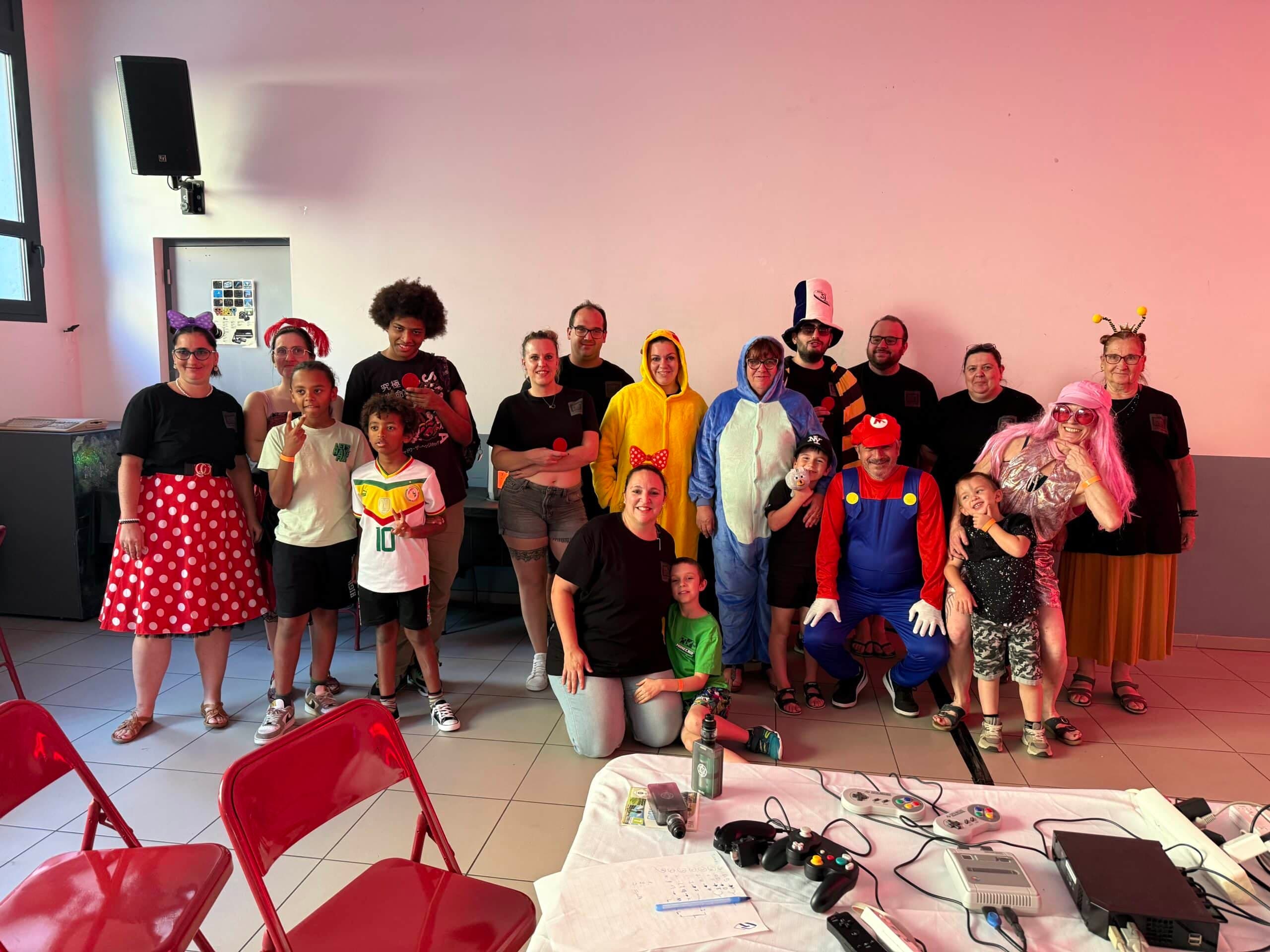 Les bénévoles du P'tit Comité avec les visiteurs lors du festival Vingrau Level One 2025 : cosplay Mario, Pokémon, Chat Botté et familles
